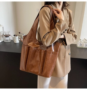 Detailed view of brown leather tote bag with large external pockets on a model