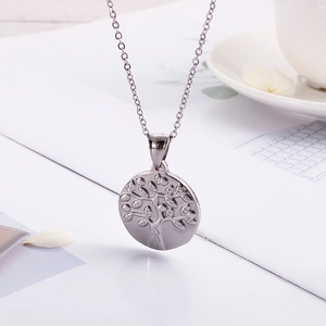 Macro detail of silver stainless steel round pendant featuring a tree of life relief design