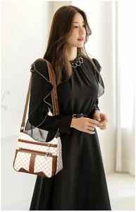 Detail of white and brown crossbody bag featuring geometric chain pattern and adjustable strap
