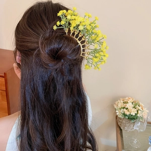 Detail of yellow floral hair pin accessory worn on a dark elegant bun hairstyle