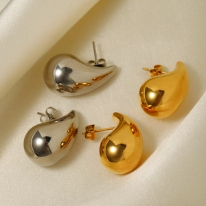 Polished 18K gold and silver waterdrop earrings on elegant white silk fabric