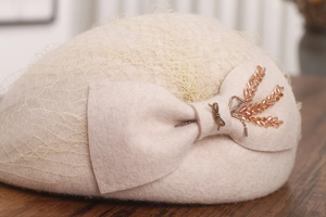 Detail of wool beret with mesh veil, oversized bow, and delicate beadwork embellishments