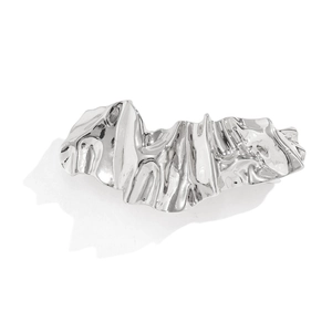 Detail of silver irregular crumpled liquid metal hair clip with high-polish mirror finish