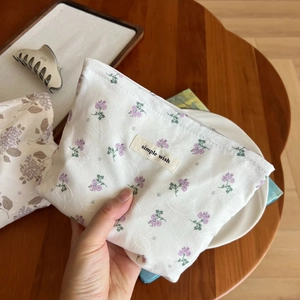Makroaufnahme einer kleinen Baumwolltasche mit lila Blumenmuster und Stoffetikett