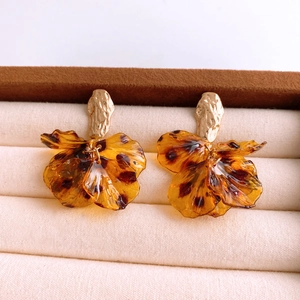 Macro detail of amber acrylic petal earrings with gold textured studs and leopard print finish