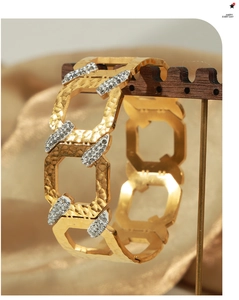 Detailed view of gold plated hollow geometric bangle with hammered texture and pavé crystals