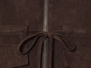 Gros plan sur la texture en daim marron foncé avec fermeture éclair et ceinture nouée