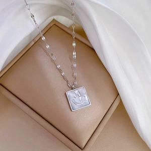 Macro shot of silver titanium steel square pendant with iridescent pearl-like texture