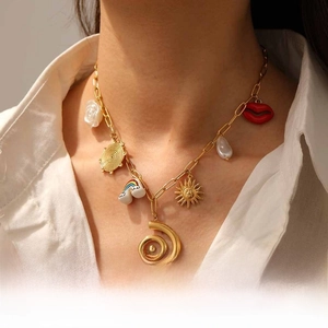 Detail of gold necklace with rainbow charms and sun pendant on a white shirt