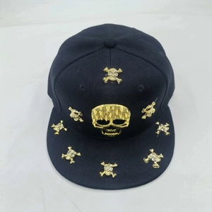 Detail of black snapback hat with metallic gold skulls and punk studs on the brim