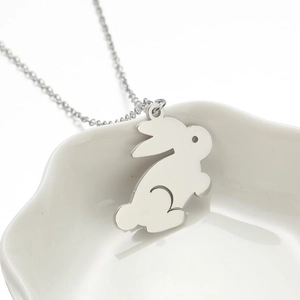 Minimalist silver rabbit pendant necklace in stainless steel on white ceramic dish