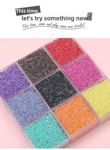Macro detail of colorful 2.5mm glass seed beads in a transparent plastic organizer box