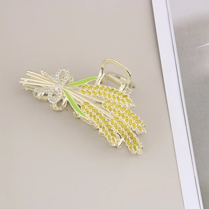 Détail d'une pince à cheveux épi de blé doré avec strass jaunes et feuilles en émail vert