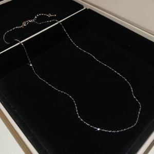 Detailed close-up of a silver stainless steel chain necklace on black velvet display