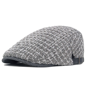 Dettaglio del tessuto in maglia tweed grigio e della fibbia in metallo del berretto