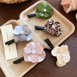 Détail de pinces à cheveux fleuries avec texture marbrée, pétales en résine et perle