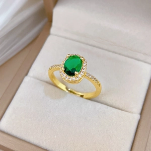 Close-up of gold ring with oval green sapphire and sparkling diamond halo on jewelry box
