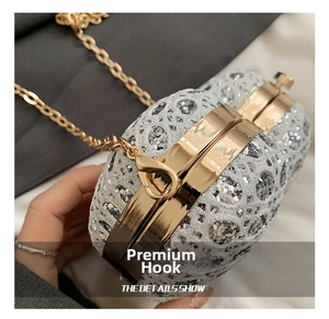 Close-up of golden metal hook and chain strap on a white sequin lace mini heart bag