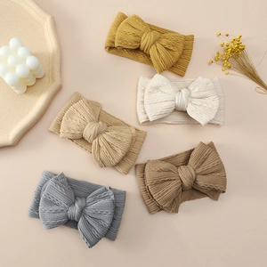 Close-up of five knitted baby bow headbands in turmeric, beige, coffee, brown and blue