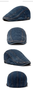 Detail view of denim flat cap with adjustable metal side buckles and orange stitching