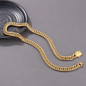 Detailed close-up of a golden stainless steel Cuban link necklace on a grey surface