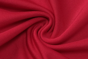 Close-up of deep red ribbed knit fabric texture showing soft folds and detailed weave