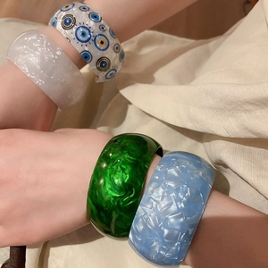 Close-up of four chunky acrylic bangles with marble texture and evil eye patterns