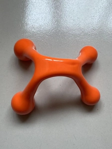 Close-up of orange manual four-point massage tool with smooth glossy plastic rollers