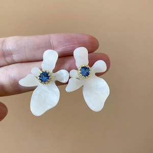 Dettagli macro di orecchini a fiore con petali di zircone blu e perno in argento