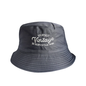 Close-up of charcoal grey bucket hat featuring white vintage embroidery and reinforced stitching