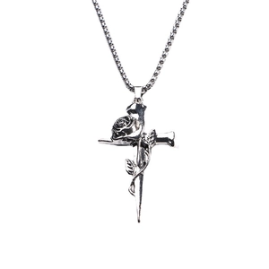 Vintage silver metal cross pendant necklace with winding rose flower on white background