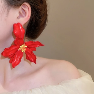 Close-up of a large red acrylic flower earring with yellow stamen on a model ear