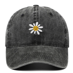 Detail der weißen Gänseblümchen-Stickerei und gelbem Smiley auf schwarzer gewaschener Denim-Kappe