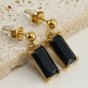 Macro shot of 18K gold earrings featuring rectangular black zircon stones and spherical studs