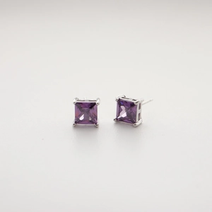 Detailed close-up of a silver square stud earring with a purple zircon in a four-claw setting
