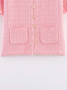 Detail of pink knitted cardigan featuring waffle texture and elegant gold buttons