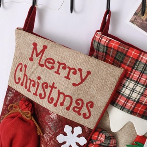 Detail of burlap Christmas stocking with Merry Christmas text and red lace fabric