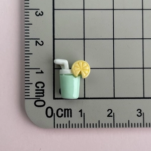 Miniature resin cold drink charm with lemon slice shown on scale for precise sizing