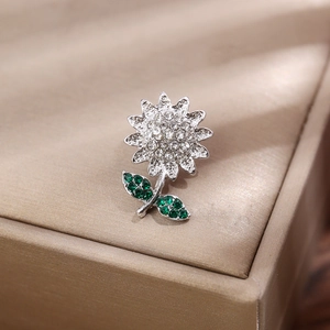 Vue macro de la broche tournesol en argent avec cristaux clairs et verts sur du satin
