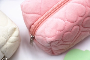 Close-up of pink plush stationery bag featuring heart quilting and silver metal zipper