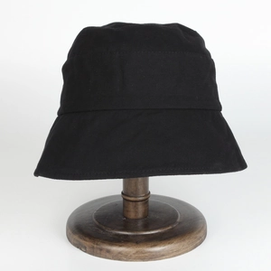 Detail of a minimalist black cotton canvas bucket hat on a vintage wooden stand