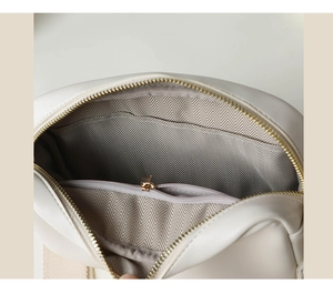 Detail view of cream bag interior with herringbone lining and golden zipper pocket