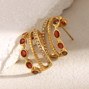 Macro shot of 18K gold plated C-shaped earrings with red zirconia and clear crystals