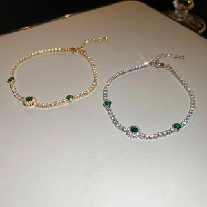 Vue détaillée de bracelets tennis dorés et argentés avec émeraudes vertes et cristaux