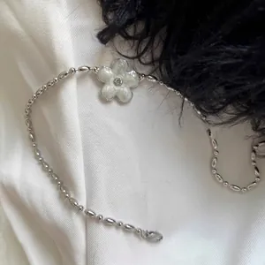 Macro shot of a silver necklace with a white flower pendant on silk and black feathers