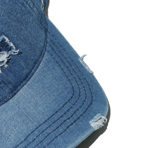 Detailed close-up of distressed denim baseball cap showing torn edges and stitching