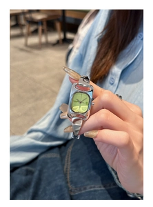 Detail of square lime green dial and silver stirrup horsebit steel bracelet watch