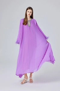 Détail d'une robe longue plissée violette avec décolleté pailleté et poignets en plumes