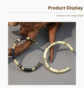 Detail of contrast enamel bamboo open bracelets in black-gold and cream-gold finishes