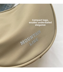 Dettaglio della borsa a mezzaluna in nylon beige con logo Mountain Line e zip argento